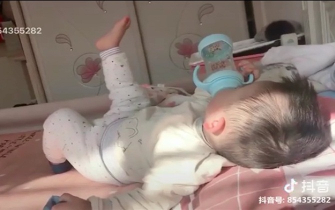 Mê tít cảnh cậu bé vừa ôm bình sữa bú vừa TAO NHÃ giơ chân múa máy hưởng thụ