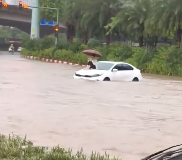 Mưa như trút, đường ngập thành sông, cô gái bất lực ngồi lên nắp capo gây xôn xao MXH